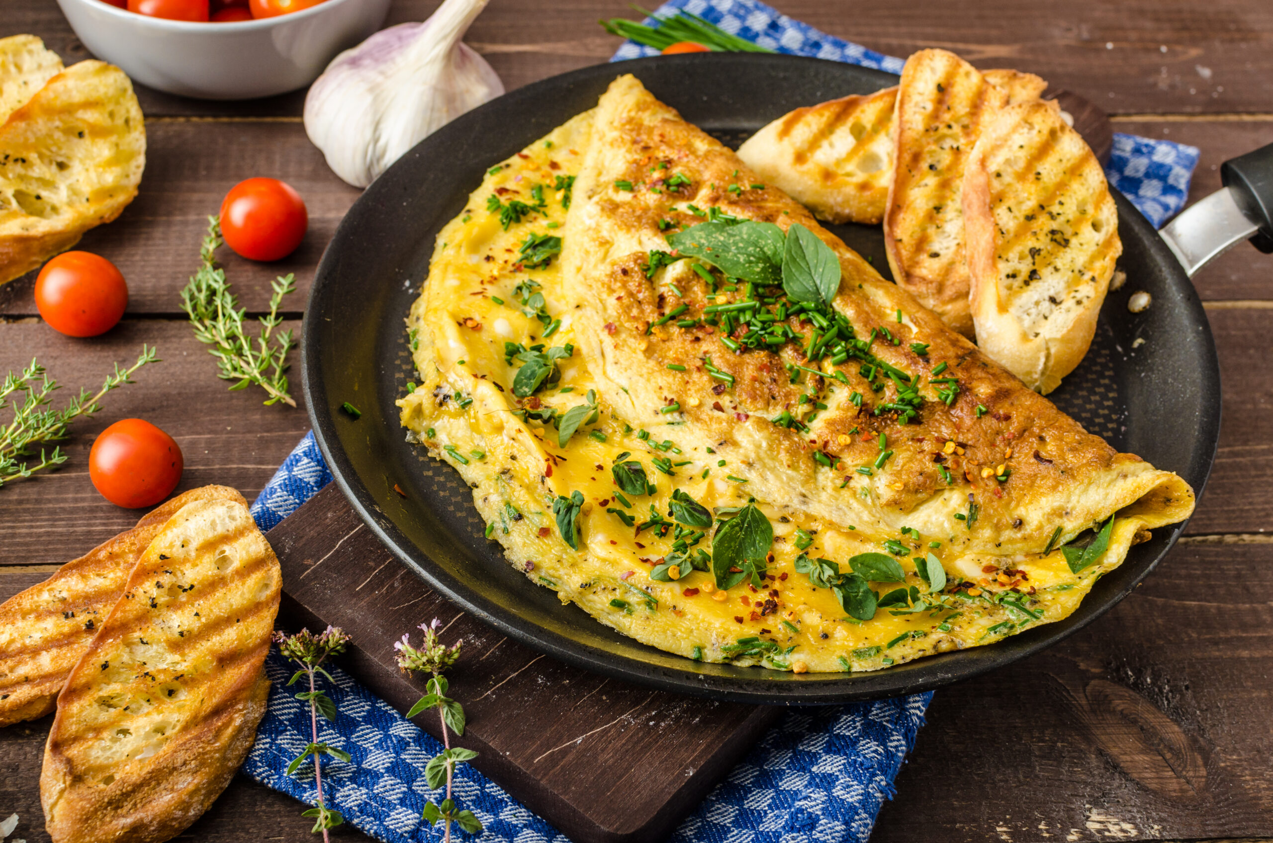 Herb omelette with chives and oregano sprinkled with chili flakes, garlic panini toasts