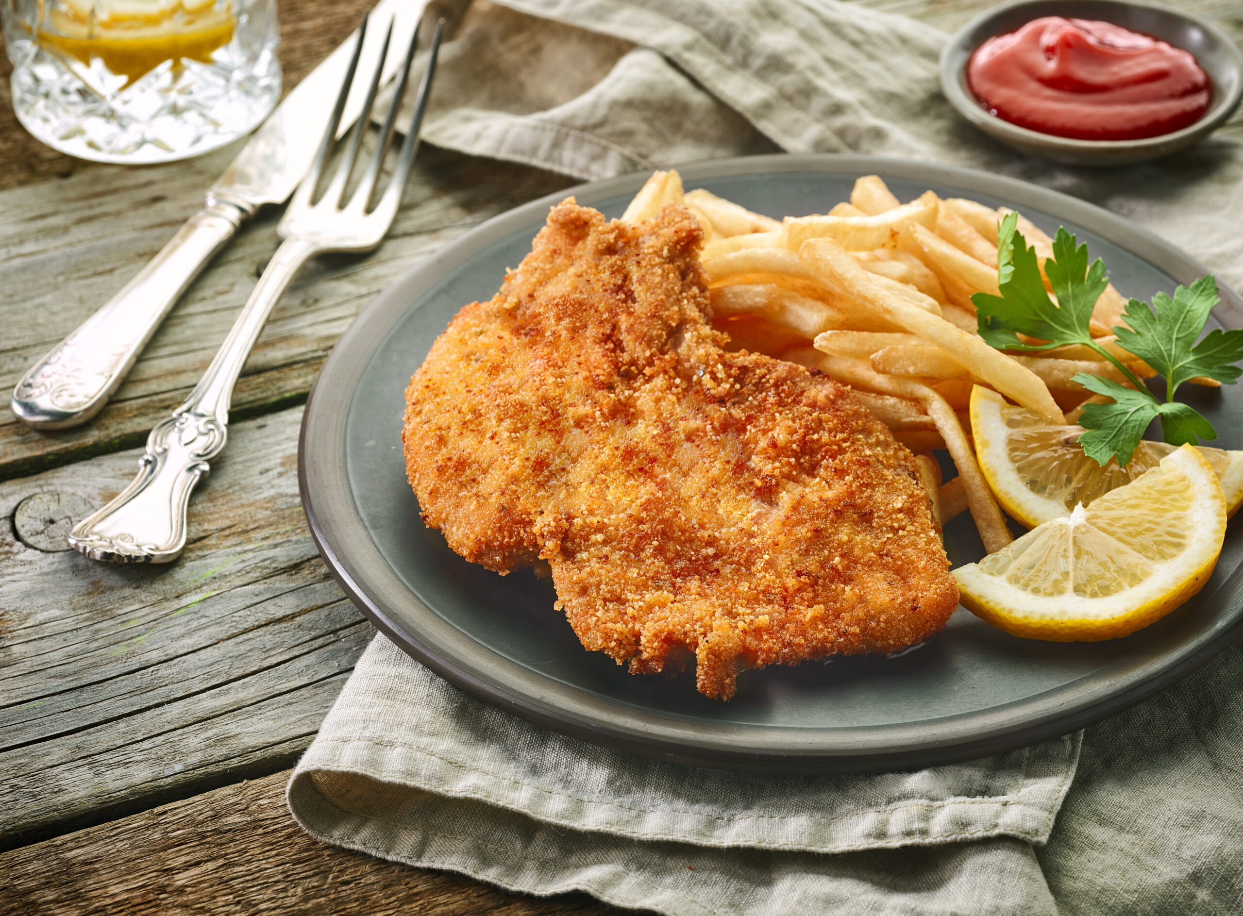 pork schnitzel and fried potatoes on wooden table