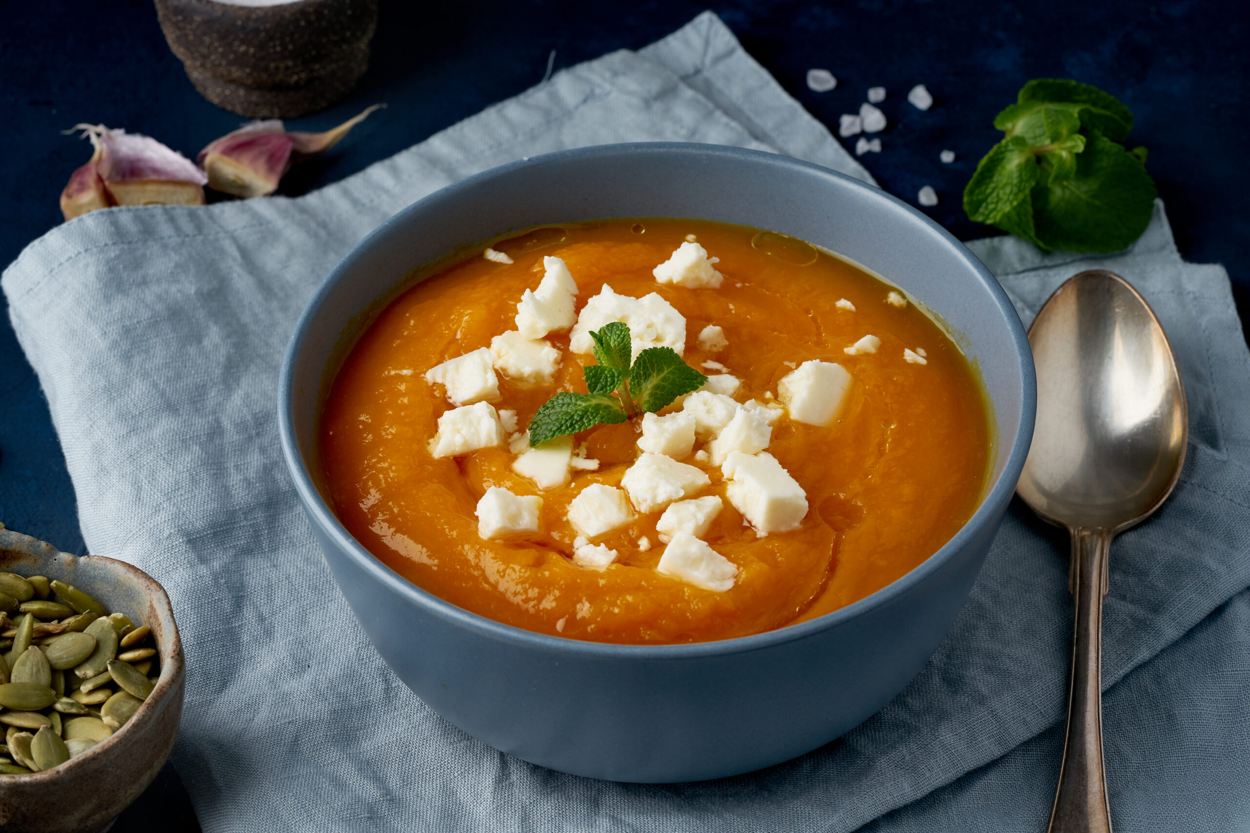 Pumpkin cream soup with a feta cheese, autumn homemade food, dark blue background, side view. Fodmap diet, lchf. Vegetarian menu, clean eating recipe